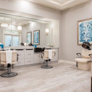 A modern hair salon featuring stylish chairs, ample lighting, and decorative wall art.