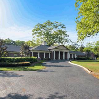 A large residential house with a circular driveway and surrounding greenery.