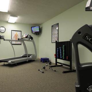 A small gym with a treadmill, weights, and exercise equipment.