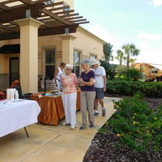 A group of people enjoying an outdoor social gathering on a patio surrounded by a garden.