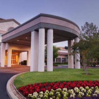 A building entrance with large columns and landscaped surroundings.