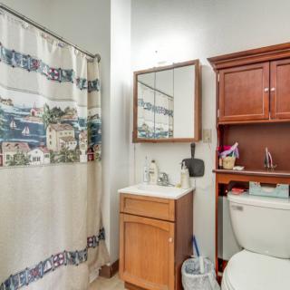 A cozy bathroom with a shower curtain, sink, mirror, and wooden cabinetry.