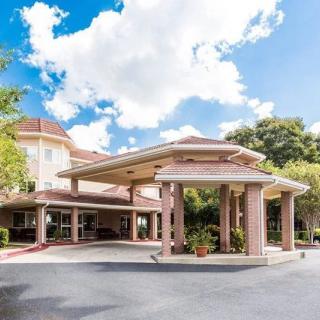 A hotel entrance with a covered driveway and surrounding greenery under a partly cloudy sky.