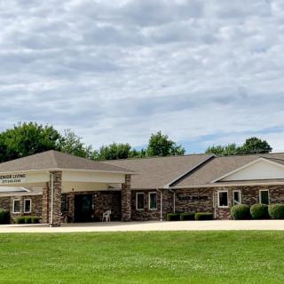 A stone building surrounded by green grass and trees under a cloudy sky.