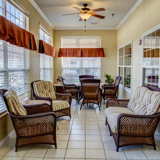 A bright sunroom with wicker furniture and large windows allowing natural light to fill the space.