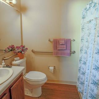 A cozy bathroom with a toilet, sink, mirror, and floral shower curtain.