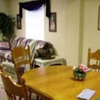 A cozy dining area with a wooden table and chairs, adjacent to a living space with a sofa and decorations.