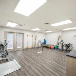 A well-lit gym space equipped with various exercise and rehabilitation equipment.