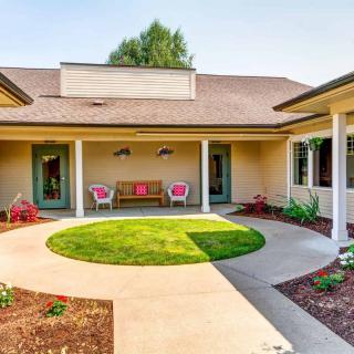 A serene courtyard with a circular lawn, surrounded by a patio and suburban house architecture.