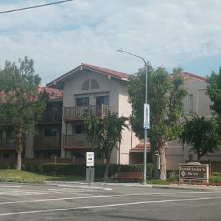 A residential apartment building surrounded by greenery and street infrastructure.