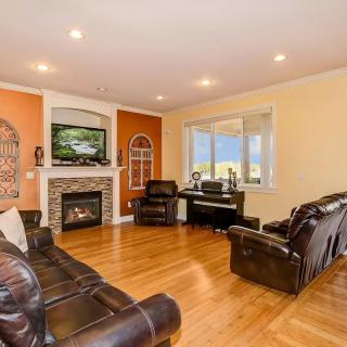 A cozy living room with leather sofas, a fireplace, and a piano by the window.