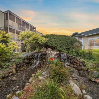 A serene garden featuring a small waterfall between buildings at sunset.