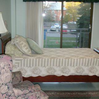 A cozy bedroom with a single bed and a chair by the window.