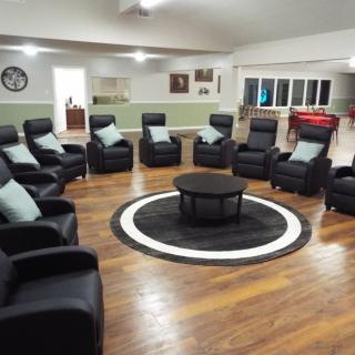 A spacious room with a circular arrangement of comfortable chairs surrounding a central table.