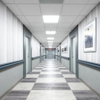 A long, empty hallway with multiple doors on either side, featuring tiled floors and overhead lighting.