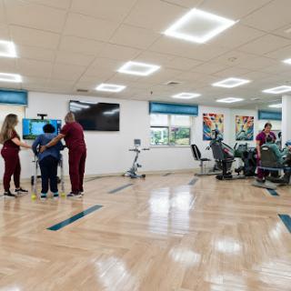 A modern physical therapy room with healthcare professionals assisting patients.