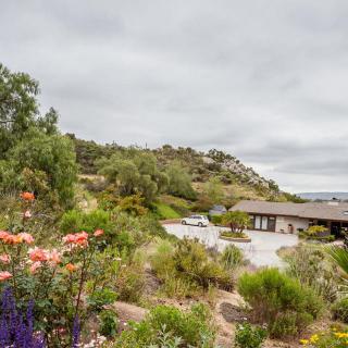 A serene landscape featuring a house surrounded by a flourishing garden and natural scenery.