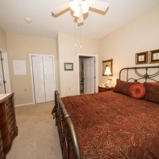A cozy bedroom featuring a large bed with decorative pillows, wooden furniture, and warm lighting.