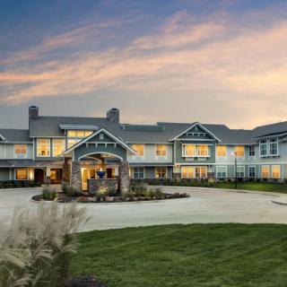 A large, modern building with a welcoming entrance set against a beautiful sunset sky.