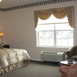 A cozy hotel room with a large bed, window, and seating area.