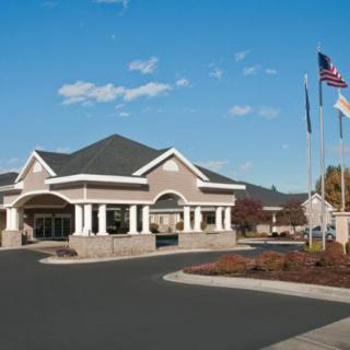 A building with a grand entrance, surrounded by flags and set against a clear sky.