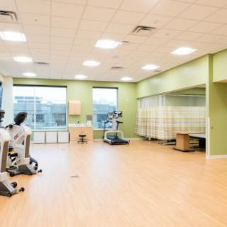 A bright and spacious physical therapy room equipped with modern exercise machines.