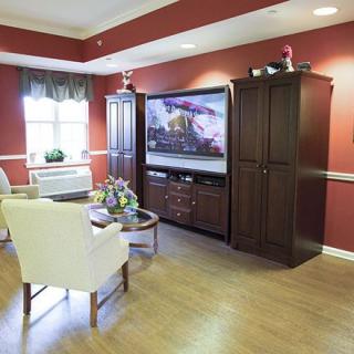 A cozy living room with a large television, elegant furniture, and warm decor.