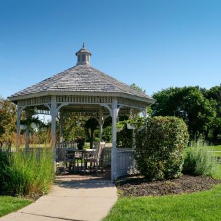 A picturesque white gazebo in a sunny park setting.
