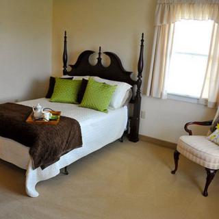 A cozy bedroom with traditional furniture featuring a bed, accent pillows, and a chair near the window.