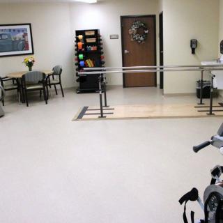 A physical therapy room equipped with exercise equipment and parallel bars.