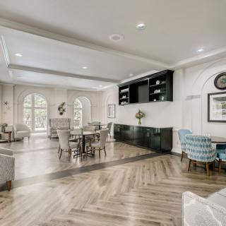 A spacious, modern living room with a dining area featuring neutral colors and elegant furnishings.