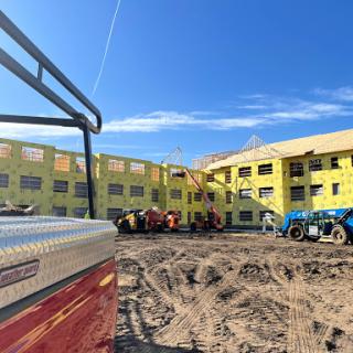 A construction site featuring a building under development, with yellow insulation visible and heavy machinery working.