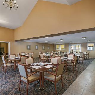 Spacious dining area with neatly arranged tables and chairs, under a warm lighting setting.