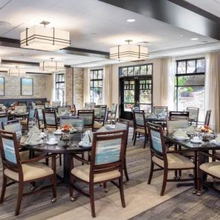 A modern and elegant dining room with neatly arranged tables and chairs under stylish lighting.