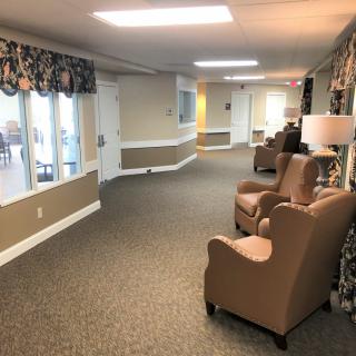 A well-lit hallway with comfortable chairs and windows along the side.