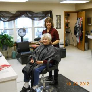 A hairstylist giving a haircut to an elderly woman in a hair salon.