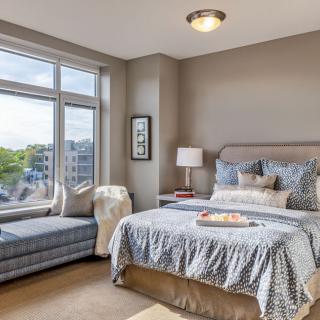 A cozy bedroom featuring a comfortable bed, window seat, and stylish decor.