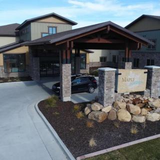 Entrance to a modern building with a covered carport and landscaped driveway.