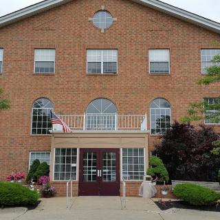 A brick building with an American flag at the entrance, surrounded by well-maintained landscaping.