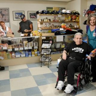 A group of people in a store, including an individual in a wheelchair, near a counter with display shelves.