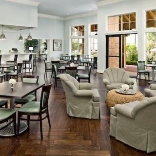 A spacious and well-lit lounge area with various seating arrangements, including tables and cushioned chairs.