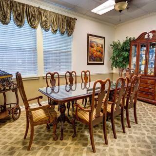 A classic dining room with a polished wooden table surrounded by matching chairs, complete with elegant drapes and a china cabinet.