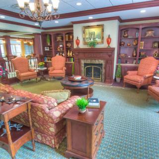 A cozy living room with classic furnishings, featuring a fireplace and built-in bookshelves.