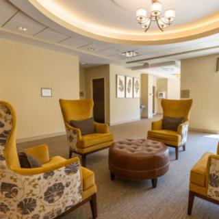 A cozy and well-lit lobby featuring comfortable armchairs and a central coffee table.