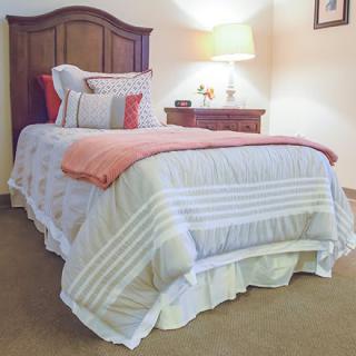 A cozy bedroom setup with a neatly made bed, nightstand, and lamp.