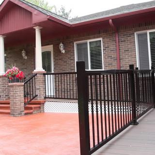 A brick house with a front porch, featuring an accessibility ramp and railings.