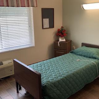 A cozy and well-lit bedroom featuring a single bed neatly made with light blue bedding.