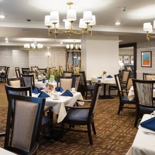 A spacious and elegant dining room with neatly arranged tables and chairs, set for a formal dining experience.