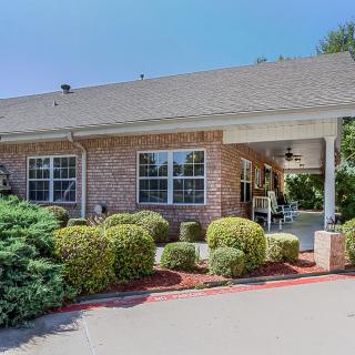 A well-maintained house with landscaped shrubs and a paved driveway.