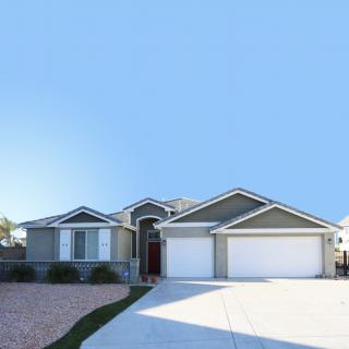 A modern single-story suburban house with a three-car garage and a spacious driveway.